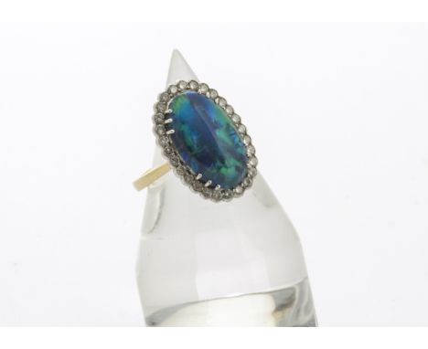 A contemporary diamond and black opal 18ct gold dress ring, the oval cabochon cut black opal in twelve claw setting surrounde