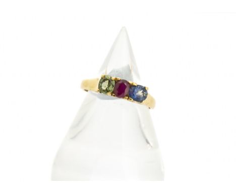 A continental yellow metal and three stone set dress ring, set with sapphire, ruby and green sapphire in claw settings on a s