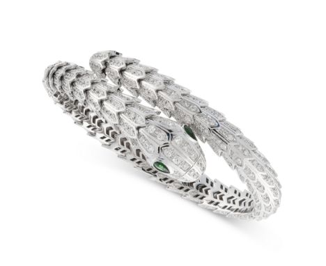 A DIAMOND AND EMERALD SNAKE BANGLE designed as a coiling snake, the articulated body jewelled allover with round cut diamonds