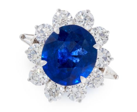 A SAPPHIRE AND DIAMOND CLUSTER RING in 18ct white gold, set with an oval cut sapphire of 4.54 carats, within a cluster of rou