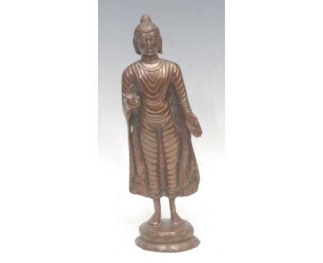 A Tibetan bronze standing Buddha figure, on a lotus pedestal with his right hand raised, left hand lowered, 24cm