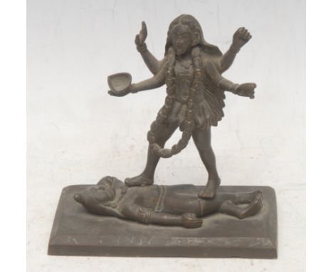 An Indian Hindu bronze figure group, Kali and Shiva, in typical pose with the goddess standing upon the god, her right foot u