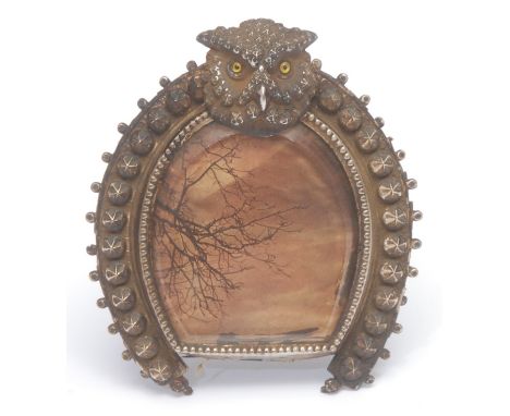 An early 20th century pressed metal novelty horseshoe shaped easel photograph frame, crested by the head of an owl, 9.5cm hig