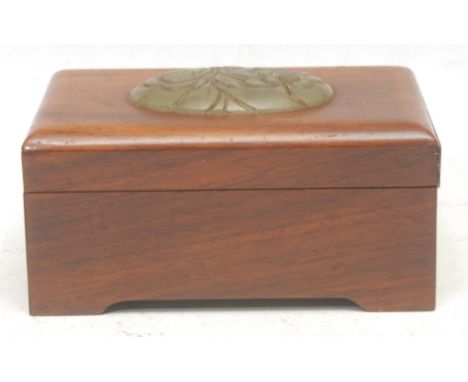 A Chinese hardwood box, the cover mounted with an oval jade panel carved with chrysanthemums, 13cm wide