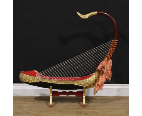 A Southeast Asian softwood saùng-gauk or arched harp on stand, boat shaped resonator, painted in vinacious and gilt, 90cm hig