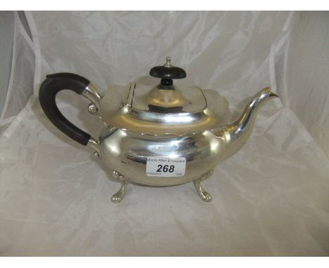 A George VI silver teapot of rounded rectangular form raised on four scroll feet, with ebony handle and finial