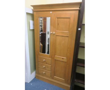 A PINE TWO DOOR WARDROBE, the moulded cornice above panelled and bevelled glazed doors with short drawers on plinth support 1