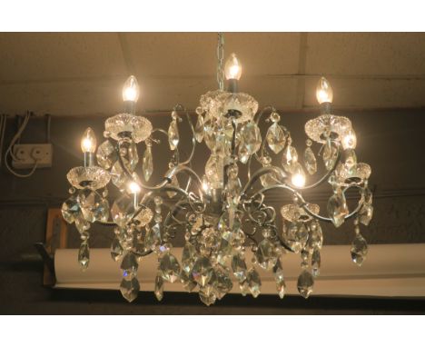 A CONTINENTAL STYLE CHROME FRAMED AND CUT GLASS EIGHT LIGHT CHANDELIER, the flying c scrolled frame with foliate cut drip pan