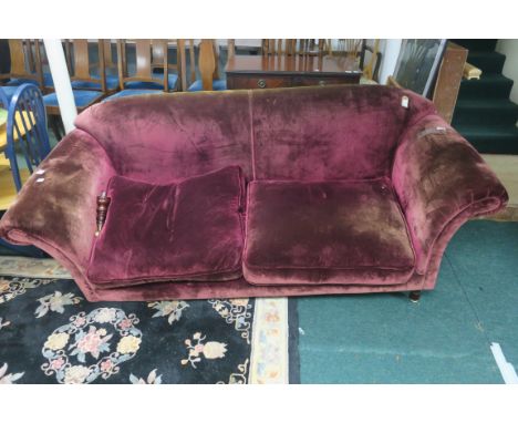 A VELVET UPHOLSTERED TWO SEATER SOFA, the overstuffed back above scrolled arms with loose cushions on turned supports with ca