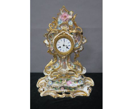 A FRENCH GLAZED PORCELAIN MANTLE CLOCK the profusely scrolled frame with gilded highlights and applied with coloured flower h