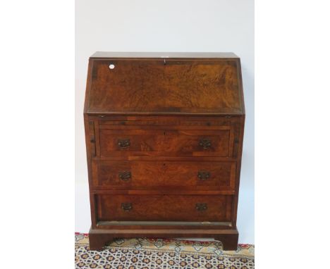 A GOOD WALNUT CROSSBANDED BUREAU, the hinged lid containing pigeon holes and drawers above three long graduated drawers on br