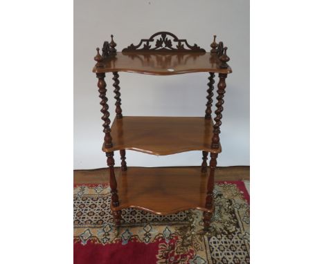 A MAHOGANY CARVED THREE TIER WHAT-NOT the serpentine shaped shelves between barley twist and ring turned column supports on c