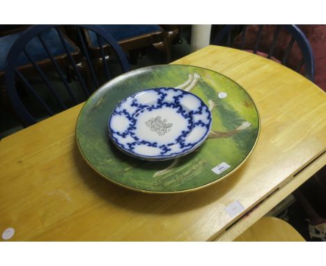 A WALL MOUNTED CIRCULAR CHARGER, painted with a dog in a landscape, signed S Ellis, together with a pair of blue and white pl