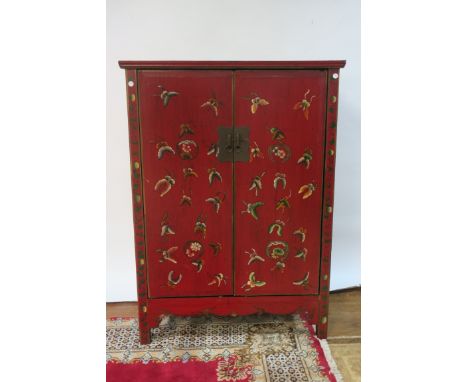 AN ORIENTAL STYLE RED PAINTED CABINET OF RECTANGULAR FORM the panelled top above a pair of cupboard doors painted with butter