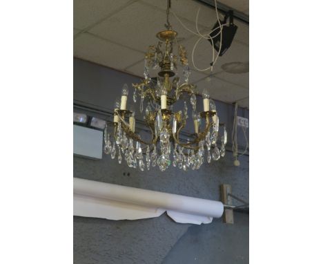 A CONTINENTAL STYLE GILT BRASS EIGHT LIGHT CHANDELIER, the foliate scrolled frame with pierced drip pans hung with pendent dr
