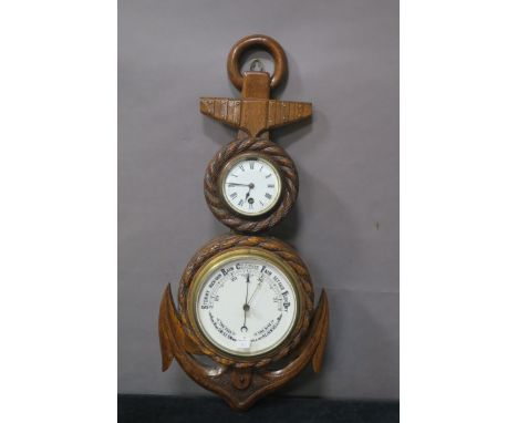 AN OAK FRAMED BAROMETER, in the form of a ships anchor the white enamelled clock face with black Roman numerals above the bar