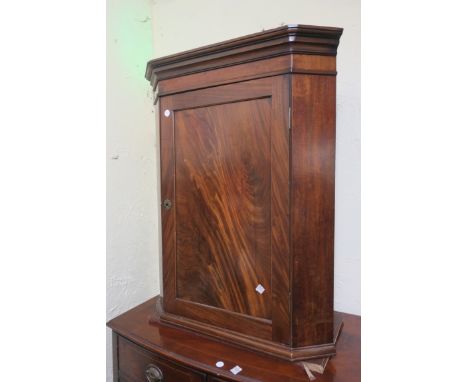 A 19TH CENTURY MAHOGANY CORNER CABINET, the moulded cornice above a plain frieze the single panelled door on outset plinth 10