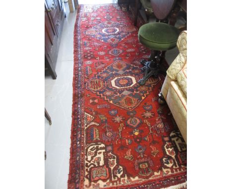 Kurdish runner with twin medallion designs on red ground, 9ft 6ins x 3ft 3ins approximately