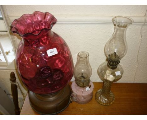 Large copper oil lamp with mauve glass shade, together with two 20th Century glass oil lamps