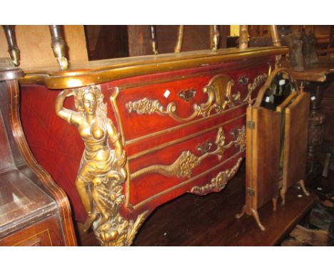 Continental reproduction gilt and red painted two drawer commode with applied carved decoration, the drawers flanked by carya