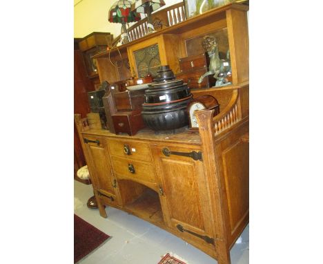 Large Art Nouveau oak side cabinet having carved and spindled gallery top above two pigeon holes with copper embossed panels 