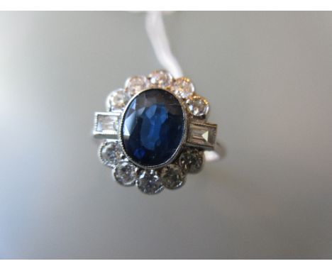 Art Deco style dress ring set with a central oval sapphire flanked by baguette diamonds and round brilliant cut diamond surro