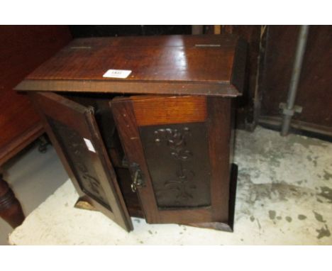 Art Nouveau oak smokers cabinet with two doors inset with embossed metal panels enclosing a fitted interior