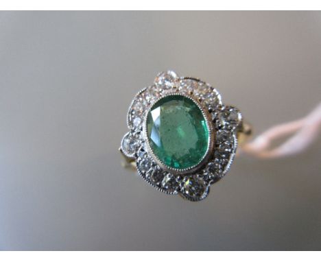 Art Deco style dress ring set with an oval central emerald within a shaped diamond surround