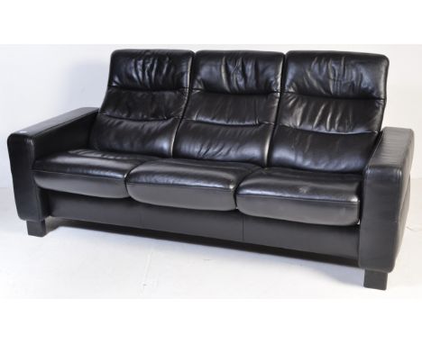 A contemporary Ekornes Stressless black leather reclining sofa having individual cinemas style reclining seats raised on upri