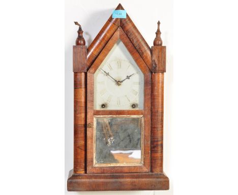 A Victorian 19th century 8 day mantel clock having a carved pediment top over a brass and enamel clock face raised on a stepp