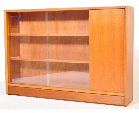 A retro vintage mid 20th century circa 1960s teak bookcase having a glazed sliding door cabinet to the left opening to reveal