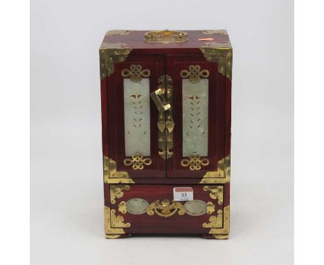 A reproduction Chinese red lacquered table top cabinet, the twin doors with carved jadeite panels, opening to reveal four sho