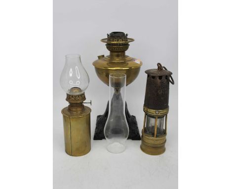 A late Victorian oil lamp having a brass font on a pierced cast iron base, together with a miner's safety lamp, and one other