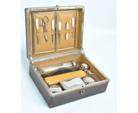 A faux leather vanity box with compartments containing metal lidded jars, clothes brush, comb, and with a manicure set in the
