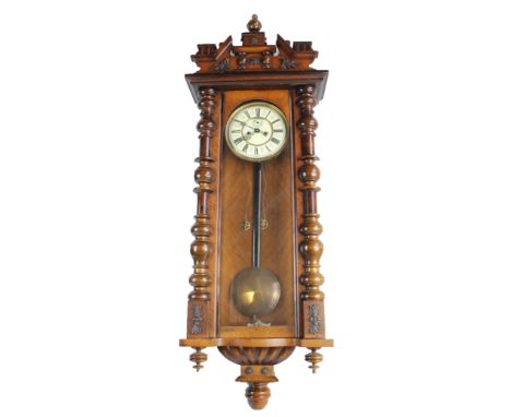 A late Victorian walnut cased eight day Vienna wall clock with carved pediment above circular dial, set with Roman numerals a