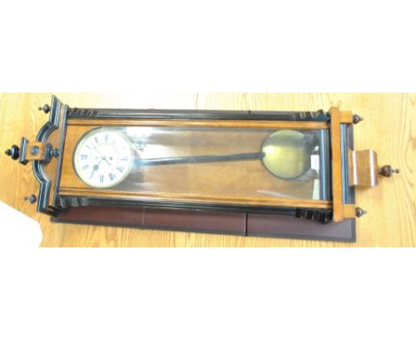 A circa 1900 part ebonised slender Vienna style wall clock with decorated dome top with three finials, the white enamel chapt