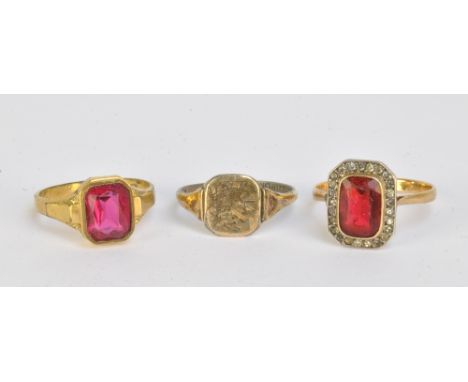 A yellow metal dress ring set with ruby coloured stone, within border of clear stones, size P (af), a further similar example