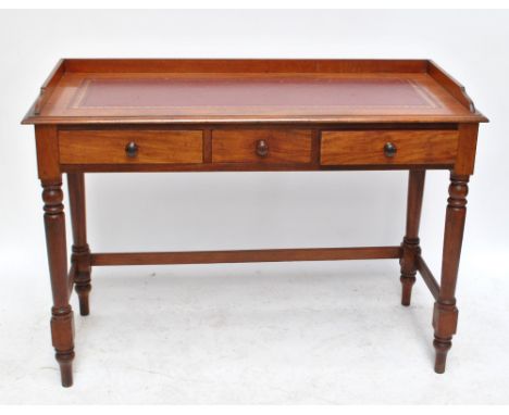 A late Victorian mahogany three drawer writing table with three quarter gallery on ring turned supports, width 116cm.