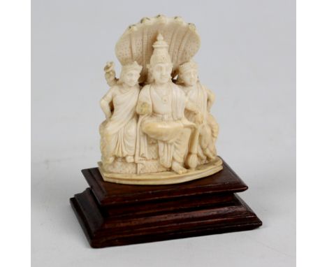 A late 19th century Indian carved ivory small figure group depicting three seated figures behind a five headed cobra mounted 