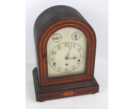 An early 20th century German mahogany and inlaid domed chiming mantel clock, the metal face set with circular chapter ring wi