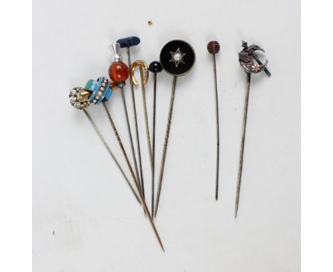 A collection of stick pins to include a gold horseshoe, a white metal crescent and axe, a circular mourning example set with 