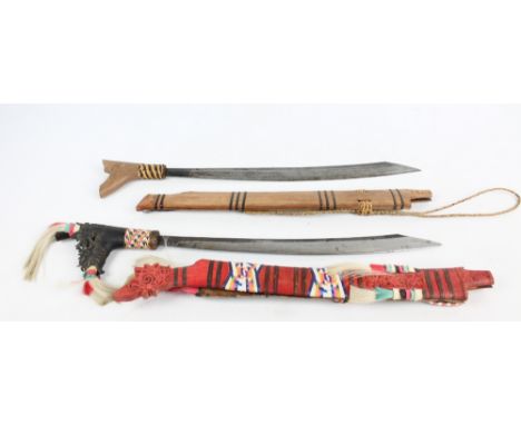 Two Dayak Parangs from Sarawak, one with a carved handle and decorative scabbard, length 77cm. 