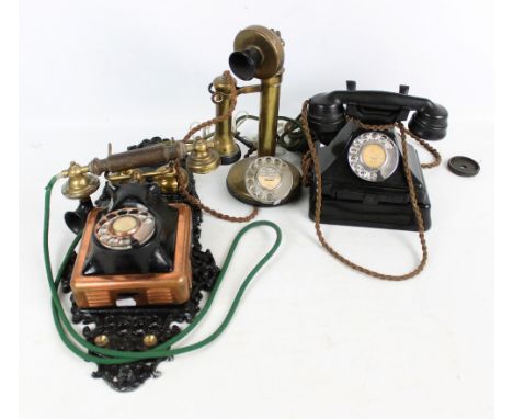 Three early 20th century telephones to include a brass candlestick phone and a wall mounted example with painted cast iron pl