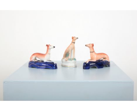 A MATCHED PAIR OF STAFFORDSHIRE SEATED GREYHOUND PEN HOLDERS19th century, paws crossed and recumbent, on cobalt blue bases, 1