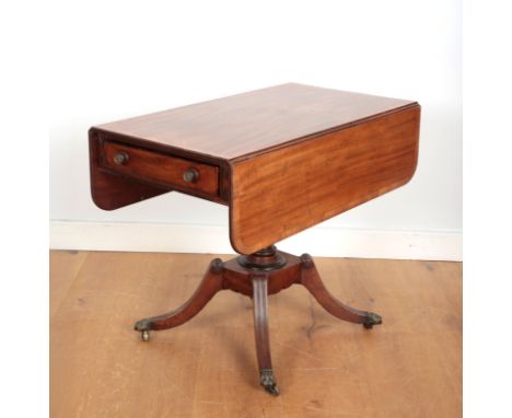 A GEORGE IV MAHOGANY DROP LEAF SOFA TABLEwith turned central column and four splayed legs with brass lion paw feet terminatin
