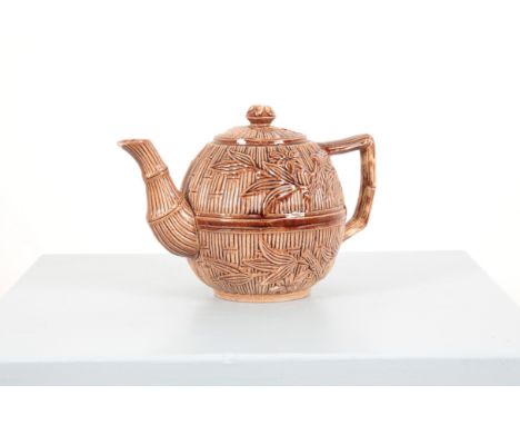 A BROWN-GLAZED AESTHETIC MOVEMENT TEAPOT of spherical form, moulded with a continuous bamboo decoration, 20cm high x 29cm wid
