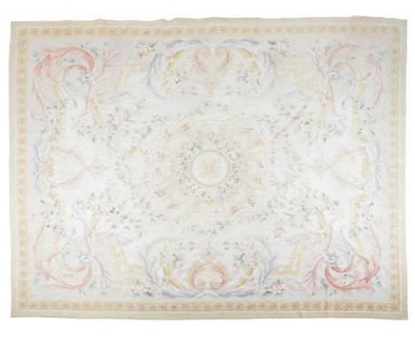 A NEEDLEPOINT CARPET OF AUBUSSON STYLE woven in pale colours with central floral medallion, ribbons and rose garlands on a pa