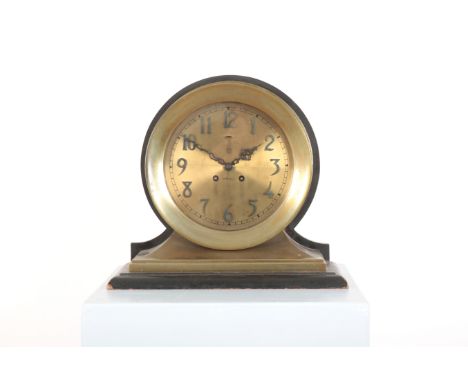 A BRASS SHIP'S CLOCK BY CROSS the brass dial with Arabic numerals, terminating on ebonised plinth, 33cm high x 36cm long x 16