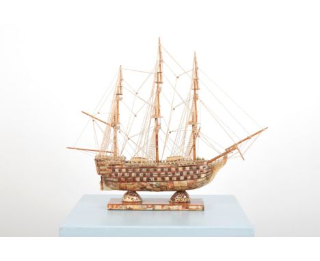 A WOODEN SCALE MODEL OF 'H.M.S. VICTORY'inlaid with mother of pearl and abalone shells, resting on two leopard conches and te