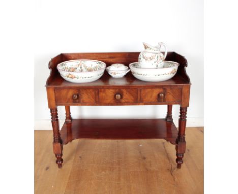 A VICTORIAN FIGURED MAHOGANY WASHSTANDthe central frieze drawer flanked by two dummy drawers, above an undertier and terminat